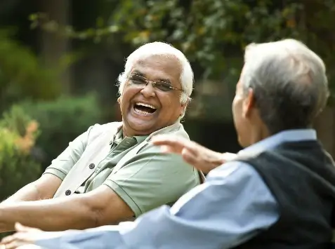 Two older men enjoying a conversation and laughing together outdoors in Allen Park, MI.
