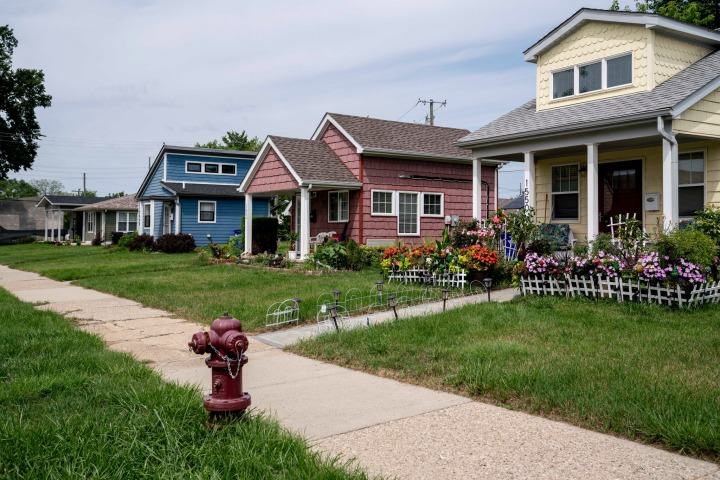 A row of vibrant houses with colorful siding and blooming flower beds in Detroit, MI